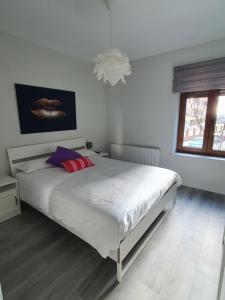 um quarto com uma cama branca com almofadas vermelhas e roxas em Casa albalunasss em Salamanca