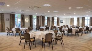 uma sala de banquetes com mesas e cadeiras brancas em Holiday Inn Kenilworth - Warwick, an IHG Hotel em Kenilworth