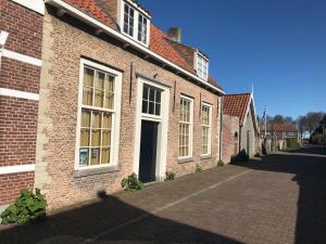 a brick building with white windows on a street at Tuinkamer in Monumentaal pand in Veere