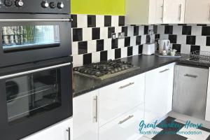 una cucina con forno a piano cottura in bianco e nero di Great Sankey Serviced Accommodation a Warrington