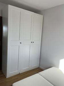 una camera bianca con armadi bianchi e un letto di Apartament Hallera a Gdynia