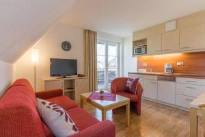 ein Wohnzimmer mit einem roten Sofa und einer Küche in der Unterkunft 2 Ferienwohnung Ostseeperle Komfort in Zingst