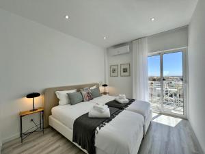a white bedroom with a large bed and a window at Faro Deluxe by Homing in Faro