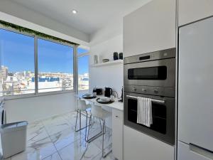 a white kitchen with a stove and a counter at Faro Deluxe by Homing in Faro