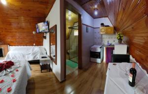 a room with a bed and a bathroom with a kitchen at Pousada Florada da Serra in Monte Verde