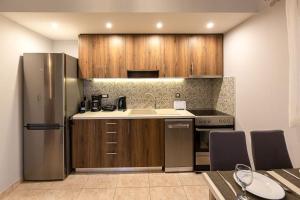 eine Küche mit Holzschränken und einem Kühlschrank aus Edelstahl in der Unterkunft Evita home karavados in Karavádhos