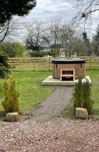 a small wooden shelter in a field with a fence at The Farmhouse, 6 bed property, Forres in Forres