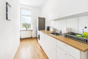 a kitchen with white cabinets and a wooden floor at Gemütliche Apartments im Herzen von Halle in Halle an der Saale