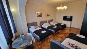 a room with three beds and a table and a tv at Czarna Owca- Pokoje Gościnne in Gniezno