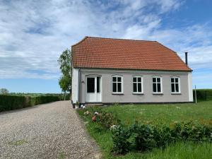 una pequeña casa blanca con techo rojo en un camino de grava en Urlaub im Haus an der Bucht, en Nordborg