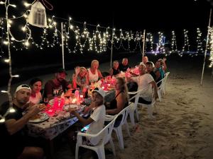 un grupo de personas sentadas en una mesa en la playa en Local Travel Beach Maldives en Hangnaameedhoo