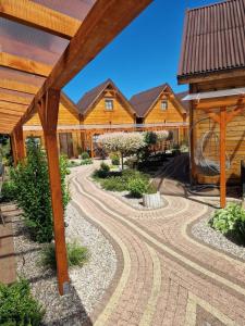 un jardín con una pérgola de madera y una casa en Domki U Ali w Rewalu en Rewal