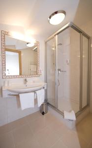 ein Bad mit einer Dusche, einem Waschbecken und einem Spiegel in der Unterkunft Hotel Bischofsmütze in Filzmoos