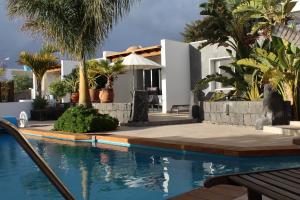 a swimming pool in front of a house with palm trees at Villa Niki mit beheiztem Gemeinschaftspool für 2 Appartments in Las Breñas