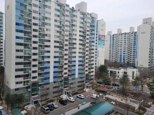 un grand bâtiment avec des voitures garées dans une ville dans l'établissement SinNaMu Family House, à Suwon