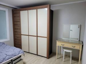 a bedroom with a bed and a dresser with a mirror at SinNaMu Family House in Suwon