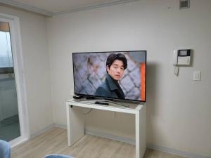 une télévision à écran plat installée au-dessus d'une table. dans l'établissement SinNaMu Family House, à Suwon