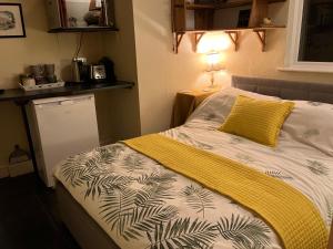 1 dormitorio con 1 cama con manta amarilla y blanca en Entire Studio with Ensuite balcony and parking, en Westcliff-on-Sea
