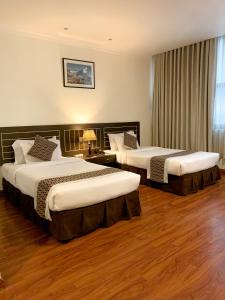 2 łóżka w pokoju hotelowym z drewnianą podłogą w obiekcie Vannasut Hotel and Spa w Katmandu