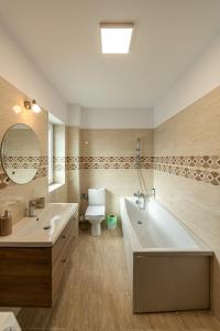a bathroom with a tub and a toilet and a sink at Citadel Apartament's in Râşnov +72 photos
