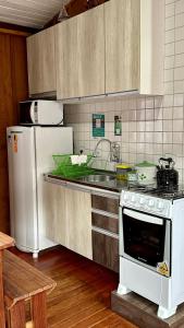 a kitchen with a white stove and a refrigerator at Casinha na Ilha do Mel - Pr in Ilha do Mel