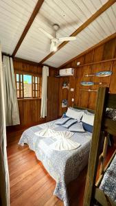 ein Schlafzimmer mit einem Bett in einem Zimmer mit Holzböden in der Unterkunft Casinha na Ilha do Mel - Pr in Ilha do Mel