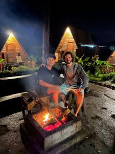 a man and a woman sitting next to a fire at Triangle House and hot spring in Kintamani