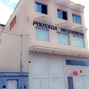 a white building with a possada residential sign on it at Pousada residencial in Curvelo