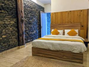 sypialnia z dużym łóżkiem i kamienną ścianą w obiekcie Gantavya Resort w mieście Pokhara