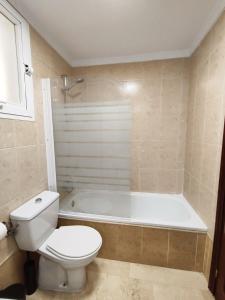 a bathroom with a toilet and a bath tub at 2BDR Sunny apartment with pool and private parking in Benalmádena in Benalmádena