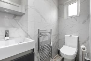 Baño blanco con aseo y lavamanos en Star London Station Road 3-Bed Oasis with Garden en The Hyde