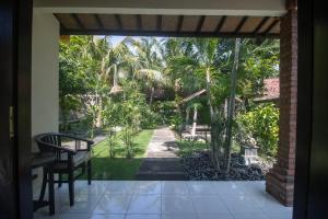 Une porte ouverte s'ouvre sur une terrasse avec des palmiers. dans l'établissement Giri Sari Guest House Pemuteran Bali, à Pemuteran