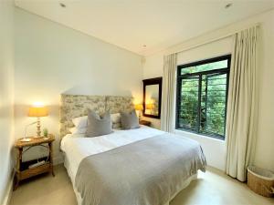 a white bedroom with a large bed and a window at Dageraad in Plettenberg Bay