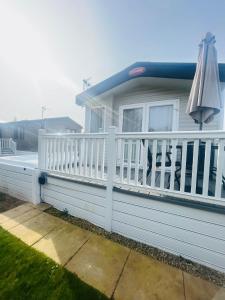a house with a white fence and an umbrella at Yorkshire Lodge with Hot Tub in York