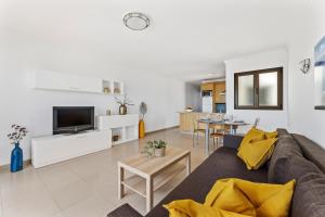 uma sala de estar com um sofá e uma televisão em Home2Book Charming Seashell Apartment Beachview em Playa Honda