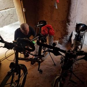 a man working on a pair of bikes in a room at Hike and Chill Homestay in Tinerhir