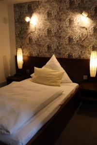 een slaapkamer met een bed met twee lampjes aan de muur bij Thuns Dorfkrug in Werdohl