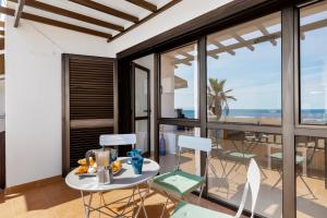 Habitación con mesa, sillas y vistas al océano. en Home2Book Charming Seashell Apartment Beachview en Playa Honda