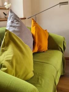 - un canapé vert avec des oreillers jaunes et gris dans l'établissement Urlaub beim Winzer, Ferienwohnung 2 mit Balkon, à Neustadt an der Weinstraße
