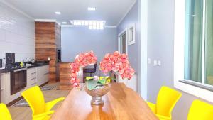 une table à manger avec des chaises jaunes et un vase avec des fleurs dans l'établissement Linda Casa Bairro tranquilo prox Cataratas, à Foz do Iguaçu