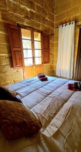 Il Mithna farmhouse with indoor heated jacuzzi pool في غرب: سرير كبير في غرفة بجدار من الطوب