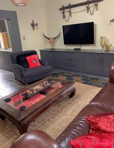 a living room with a couch and a tv at Chivay Country Cottages in Rooiberg