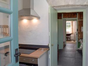 a kitchen with a stove top oven next to a hallway at Gamekeepers Cottage in Newchapel