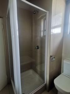 a shower with a glass door next to a toilet at Polela Cottage in Margate