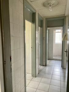 a hallway of an empty bathroom with white tiles at Stay Inn Lodge Randfontein in Randfontein
