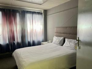 a bedroom with a large white bed and a window at Stay Inn Lodge Randfontein in Randfontein