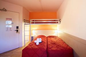 a bedroom with a red bed with a white stuffed animal at Première Classe Amiens in Amiens