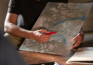 a man holding a red pin on a map at Explora en Parque Nacional Patagonia in Cochrane