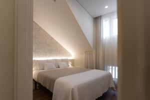 1 dormitorio con 1 cama grande con manta blanca en APARTAMENTOS TURISTICOS QUINTA LA PLAZA en Quintanadueñas
