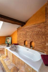 a bath tub in a room with a brick wall at Domaine de la Ruisseliere in Lacenas